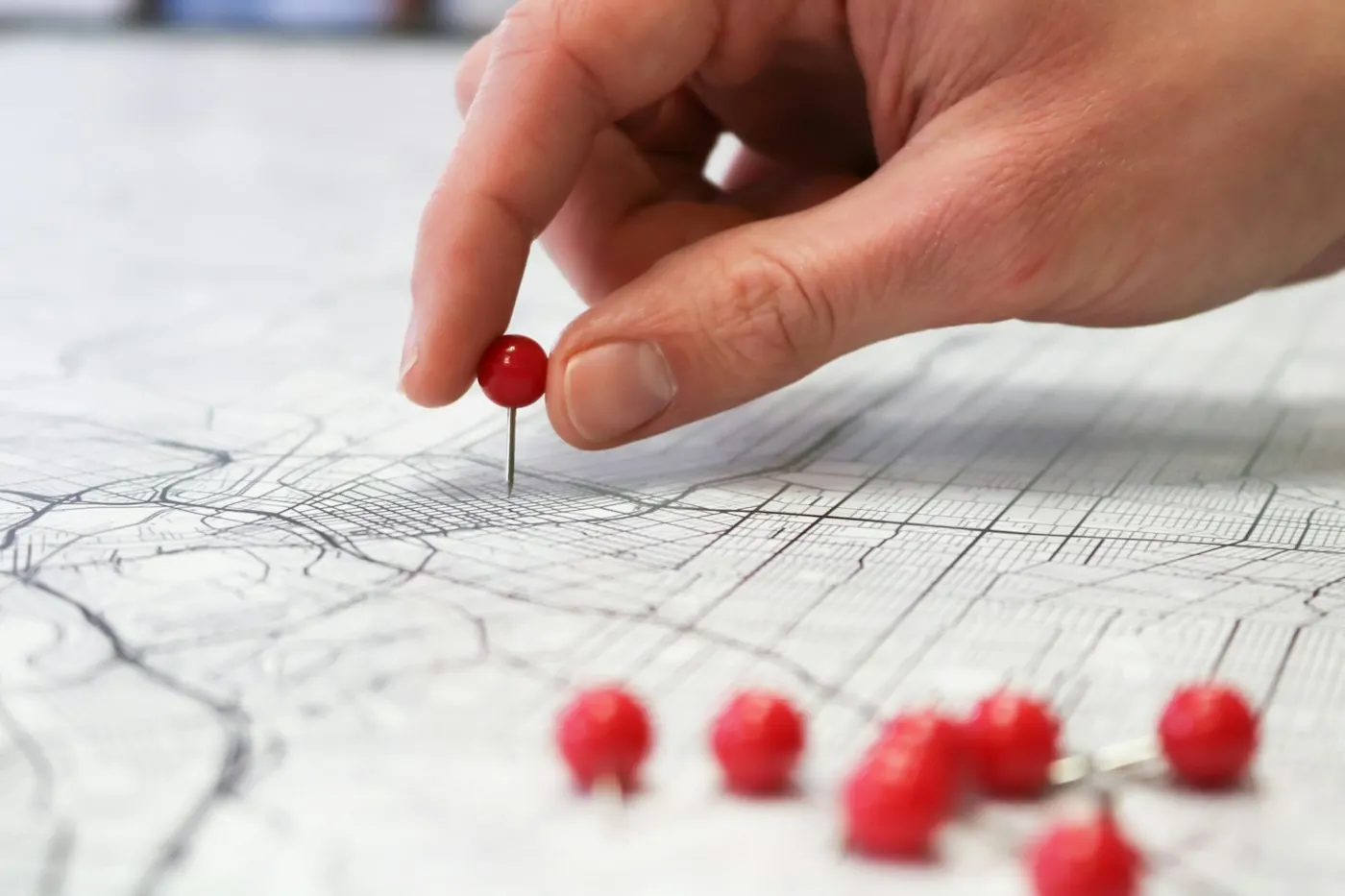 Une main pose une épingle sur une carte