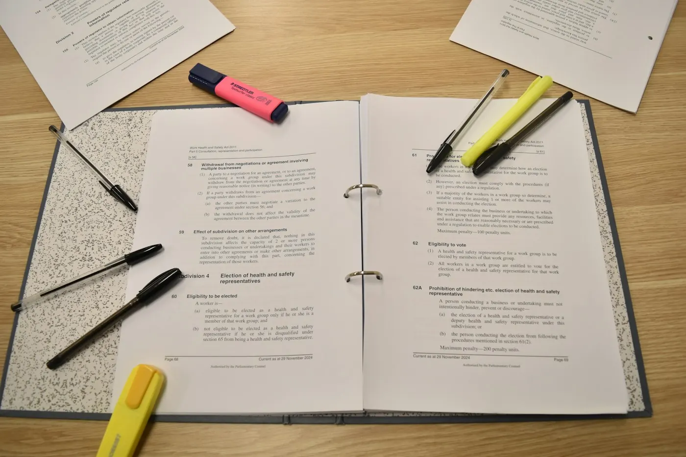 Un règlement annoté dans un classeur ouvert, surligneurs à côté